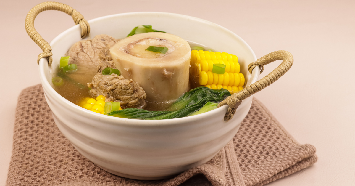 An image showing a bowl of bone broth with ingredients like bones and vegetables.